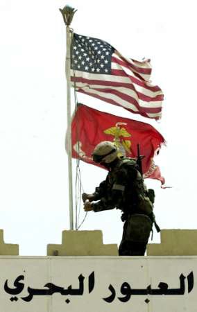 In Umm Qasr, Iraq, A Marine replaces the Iraqi flag at the entrance to Iraq's main port with the US and Marine Corps colors.